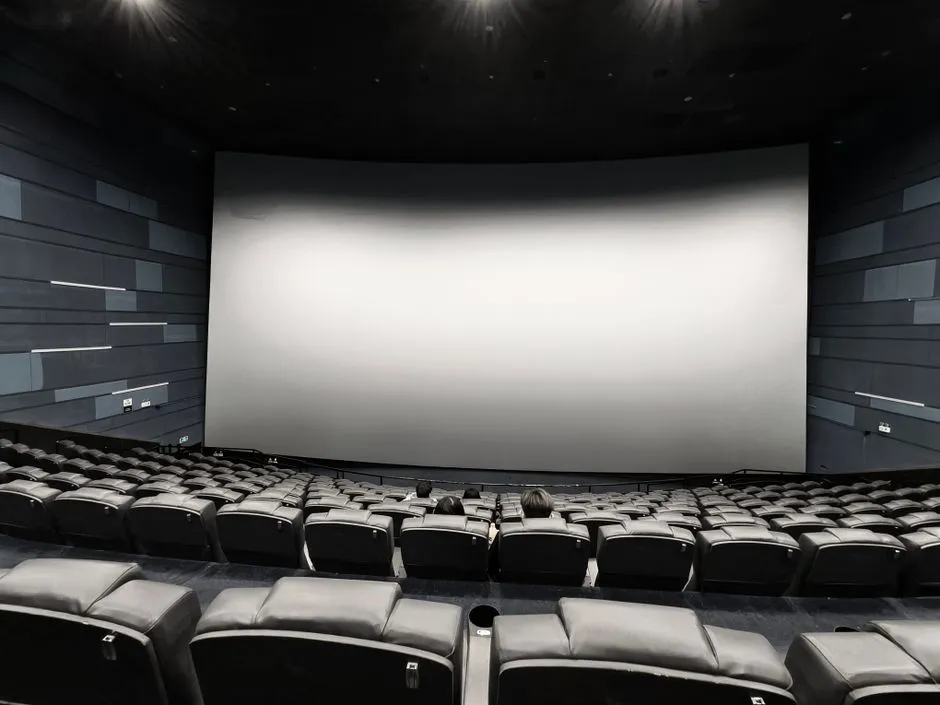 Rows of empty seats facing a large screen in a movie theater auditorium